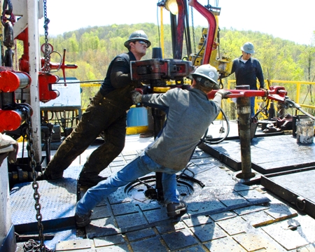 Workers move a section of well casing into place at a natural gas well site near Burlington, Pa.